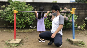 お父さんの足に両足をのせて逆上がりをする女の子