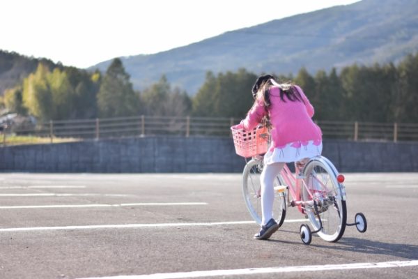 補助輪付きの自転車に乗る女の子