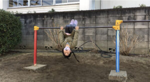 手をつかないで鉄棒のこうもりをする女の子