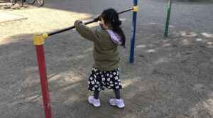 一人で鉄棒のこうもりをする女の子