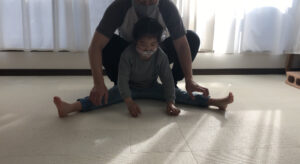開脚をする女の子を補助するお父さん