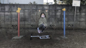 鉄棒のブランコで着地後に姿勢を戻す女の子