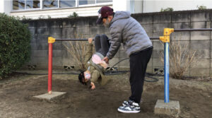 鉄棒のこうもりで両手をはなす女の子
