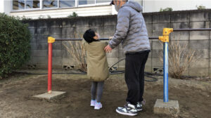 鉄棒のこうもりで片手をはなす女の子