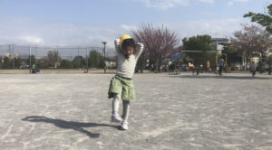 足をチョキにしながらボールをオーバースローで投げる女の子