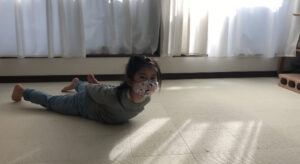 うつ伏せになって手を後ろで組んで起き上がる女の子