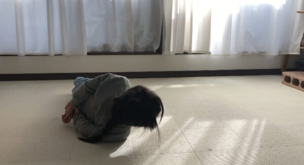 うつ伏せから横向きになって後ろで手を組んで起き上がる女の子