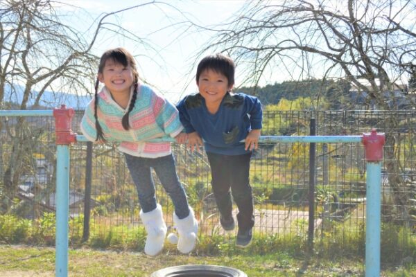 鉄棒でつばめをしている男の子と女の子