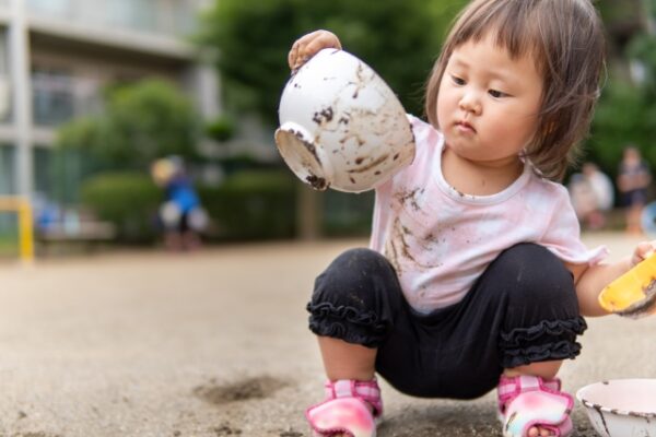 バケツを使って泥遊びをする女の子