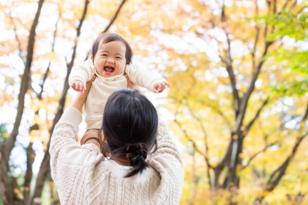 赤ちゃんを高く持ち上げているお母さん