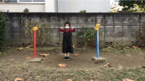 鉄棒に片足をのせて前に下りる女の子