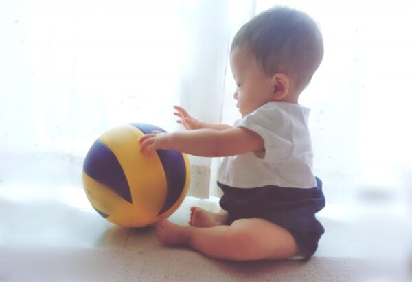 座ってボールで遊んでいる赤ちゃん