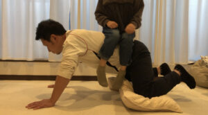 背中に娘が横向きに座って腕立て伏せをするお父さん