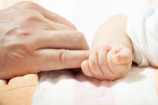 親の人差し指を握っている赤ちゃんの手