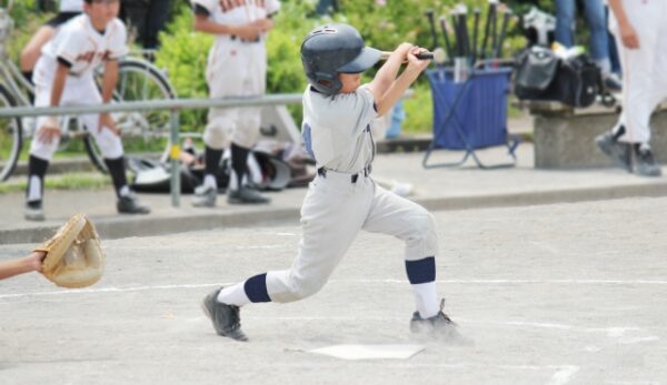 野球でボールを打つ少年